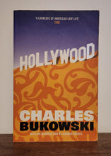 Load image into Gallery viewer, Book titled 'Hollywood' by Charles Bukowski on a wooden surface.