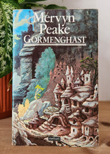 Load image into Gallery viewer, Book titled 'Gormenghast' by Mervyn Peake on a wooden surface with a plant in the background.