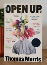 Load image into Gallery viewer, Book titled 'Open Up' by Thomas Morris on a wooden surface with a plant in the background