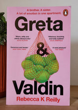 Load image into Gallery viewer, Book titled 'Greta & Valdin' by Rebecca K. Reilly on a shelf with a plant in the foreground.