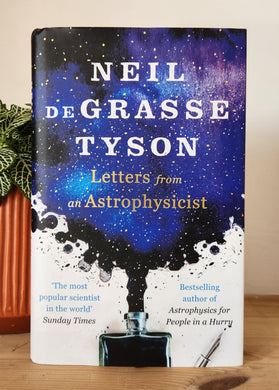 Book titled 'Letters from an Astrophysicist' by Neil deGrasse Tyson on a wooden surface.