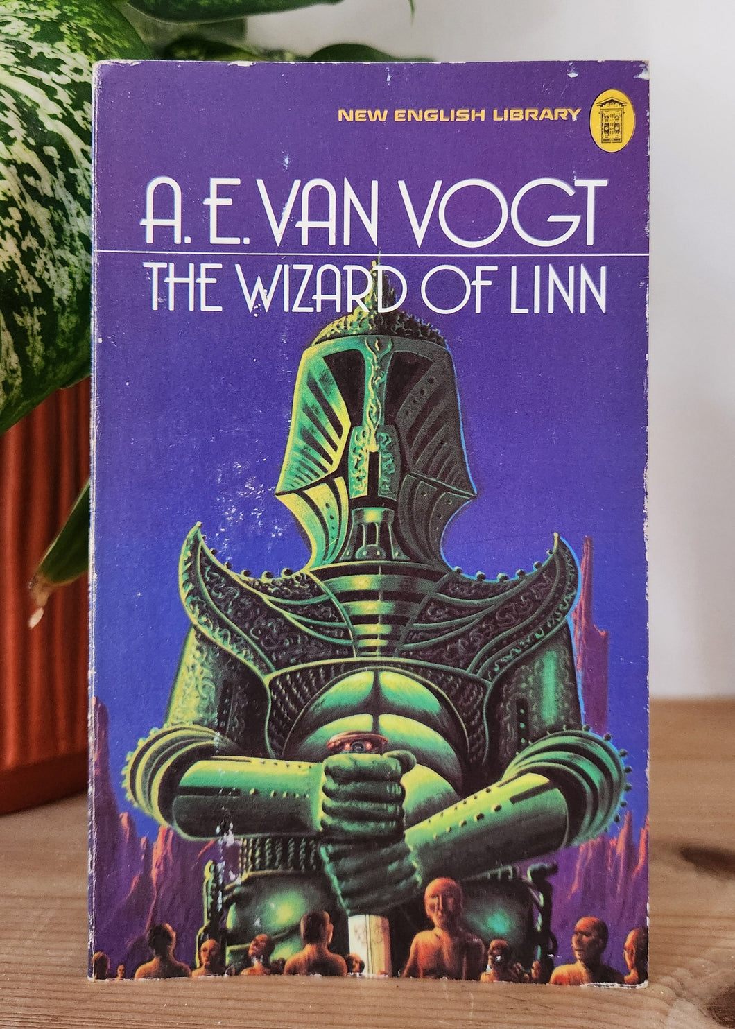Book titled 'The Wizard of Linin' by A.E. Van Vogt on a wooden surface with a plant in the background